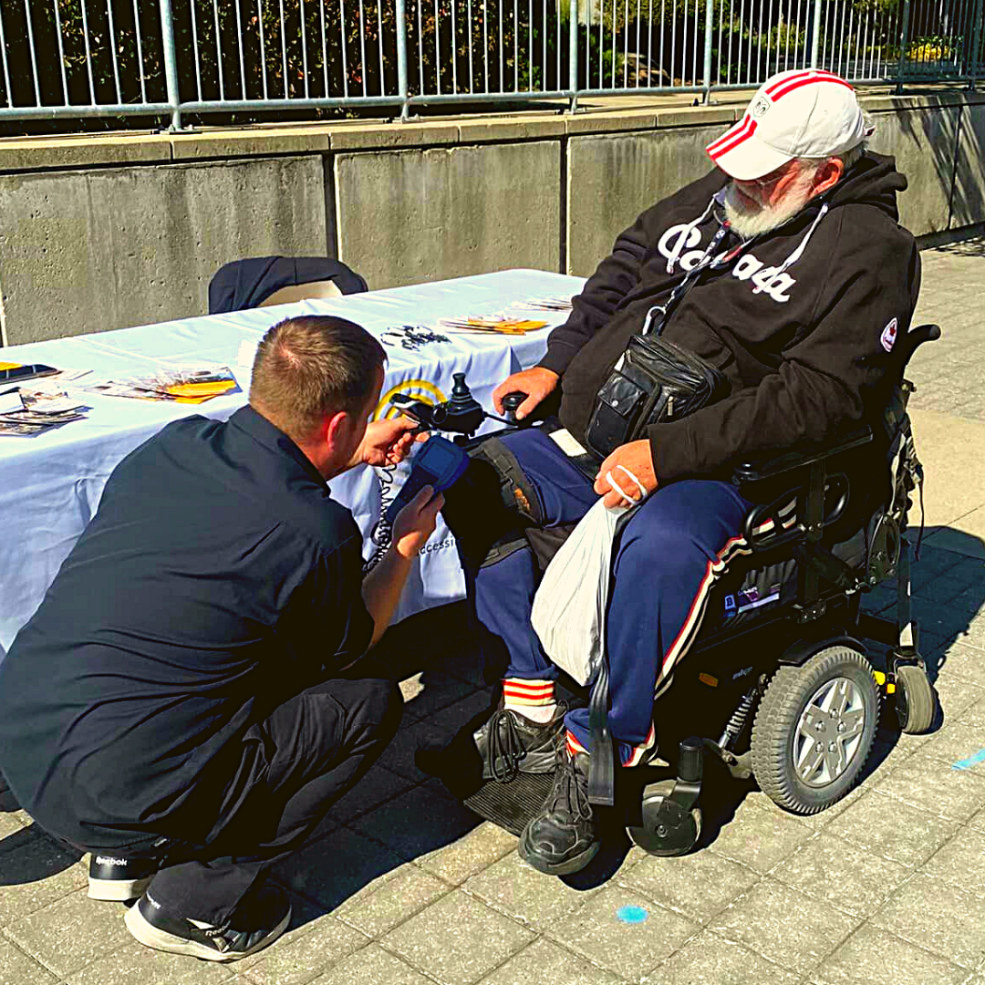 Motion employee kneeling down to assist client in power wheelchair